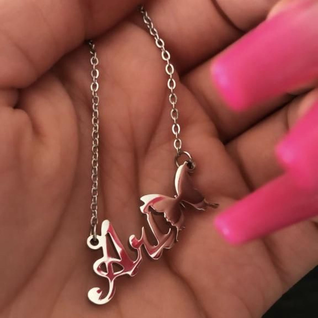 A hand holding a silver necklace with a butterfly pendant.