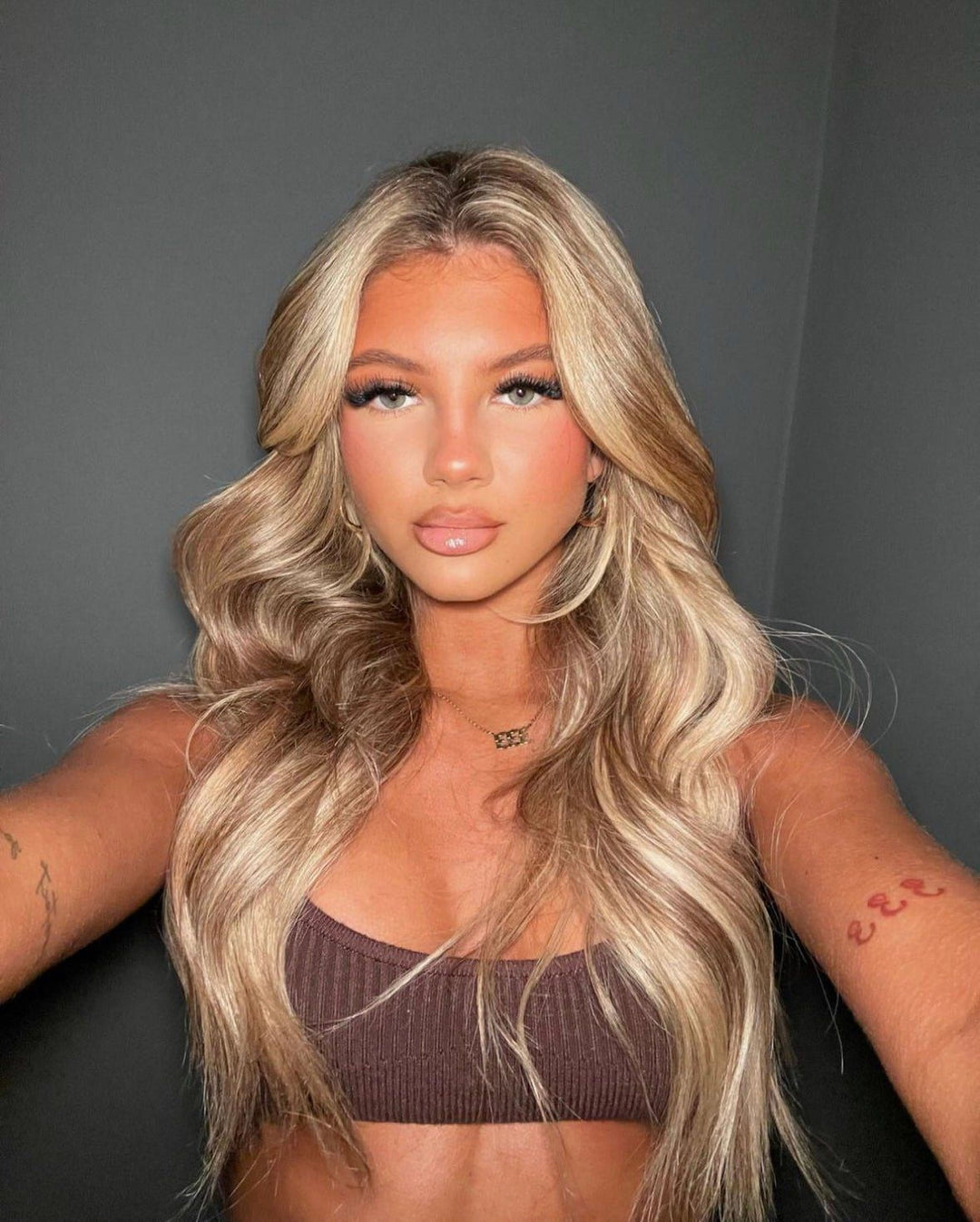 A woman with long, wavy blonde hair and makeup posing for a selfie.