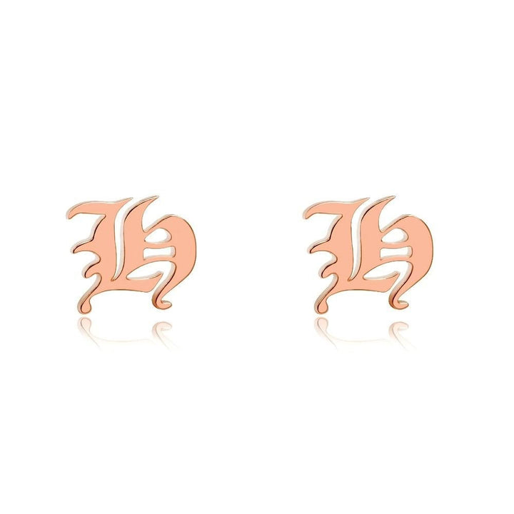 two gold-colored earrings with the letter &