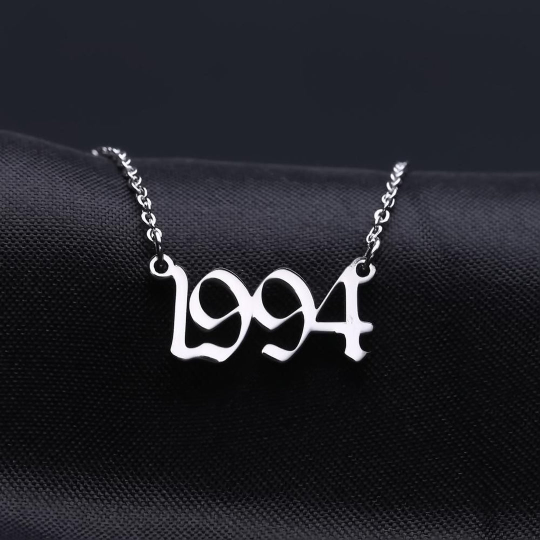 A necklace with the year "1994" engraved on it, displayed against a dark background.