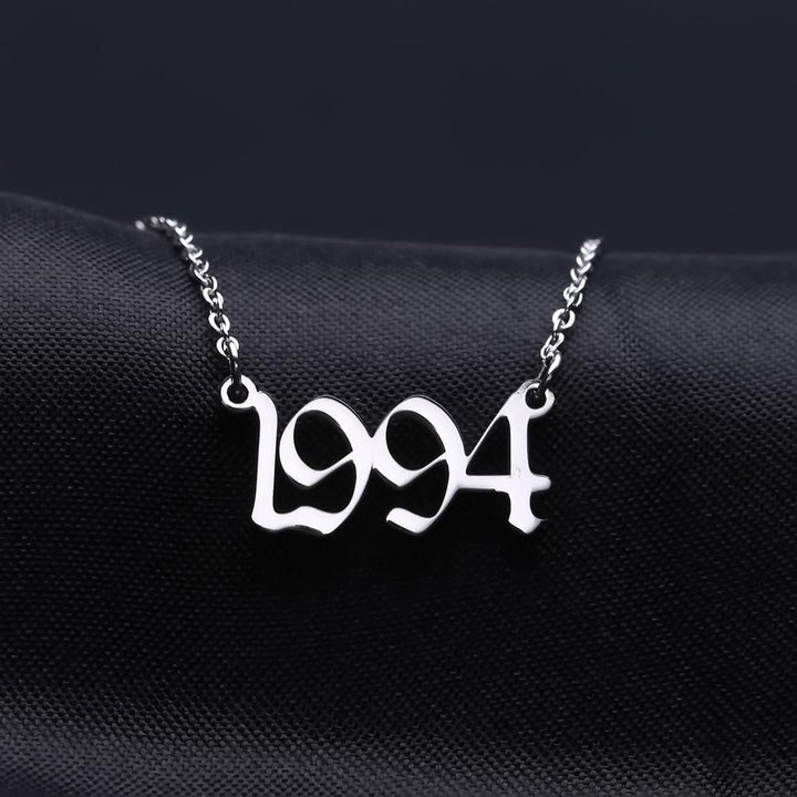 A necklace with the year "1994" engraved on it, displayed against a dark background.