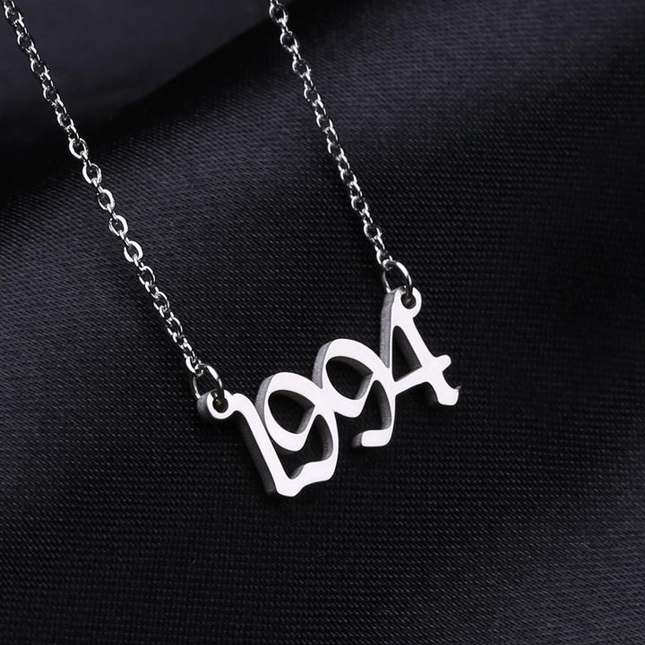 A necklace with the year "1994" engraved on it, displayed against a dark background.