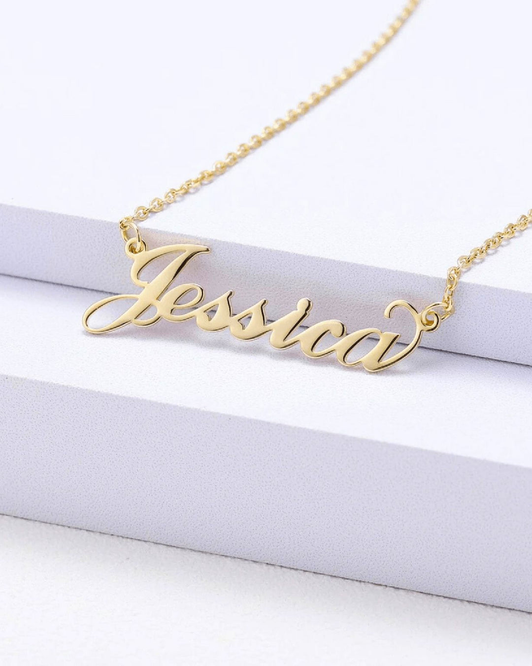A gold-colored necklace with the name " Jessica" engraved on it.