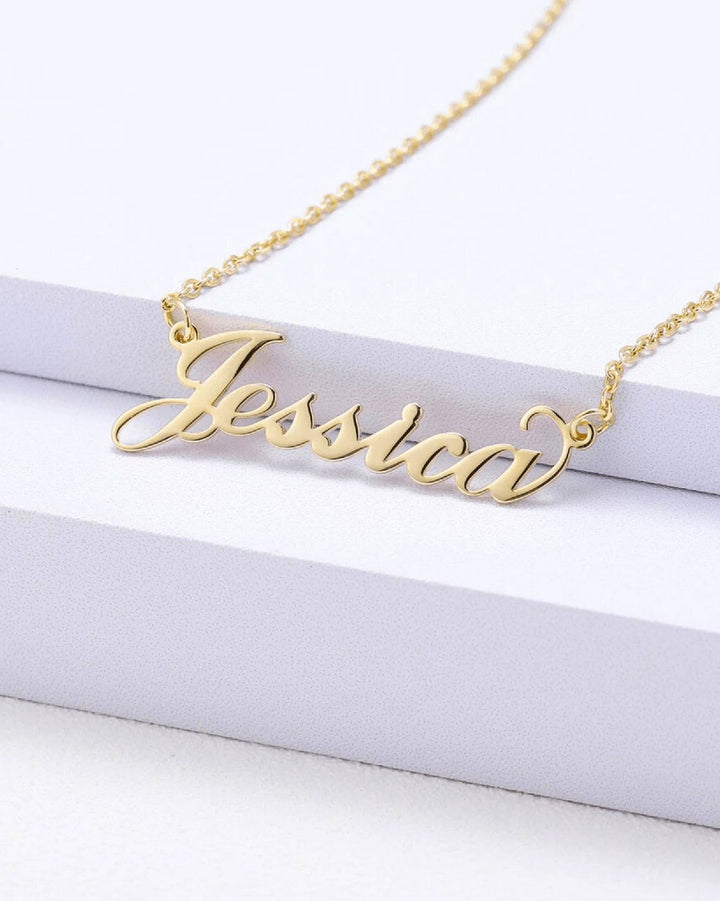A gold-colored necklace with the name " Jessica" engraved on it.