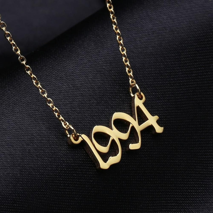 A gold-colored necklace with the year "1994" engraved on it.
