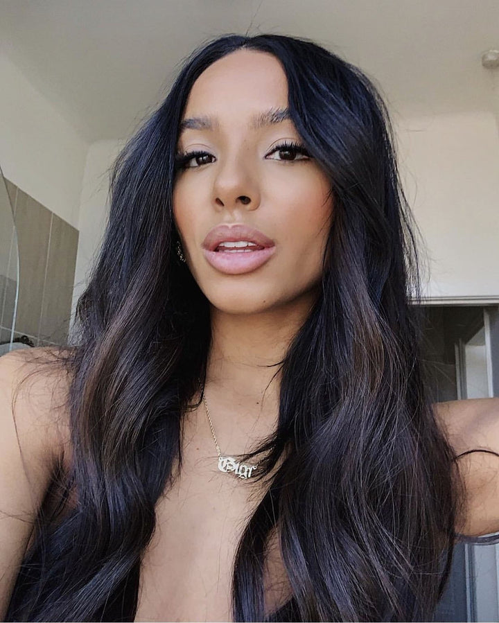 A woman with long dark hair and a necklace is shown in a close-up portrait, looking directly at the camera.