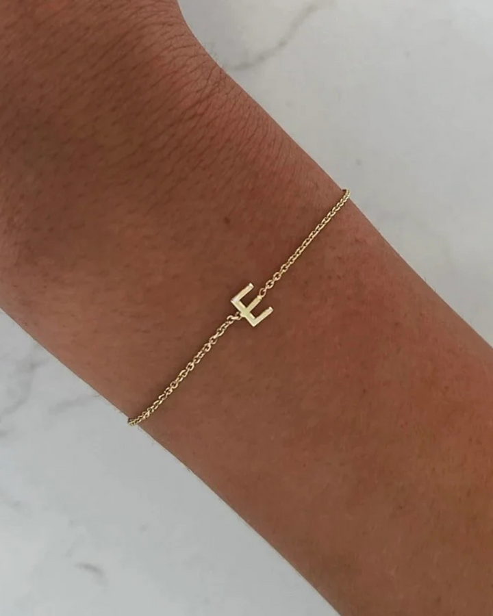A gold bracelet with a single letter &