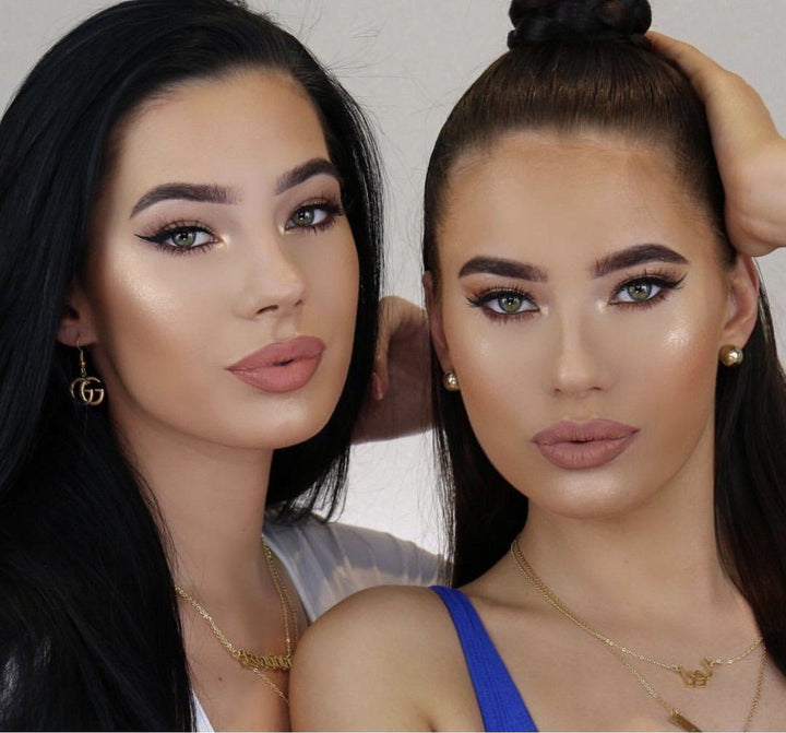 Two women with dark hair and makeup posing together.