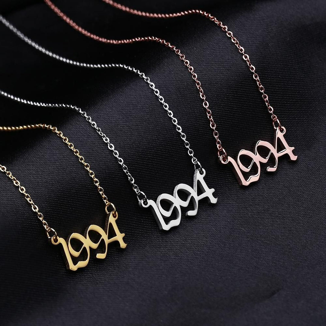 Three necklaces with the year "1994" engraved on them, in different colors: gold, silver, and pink.