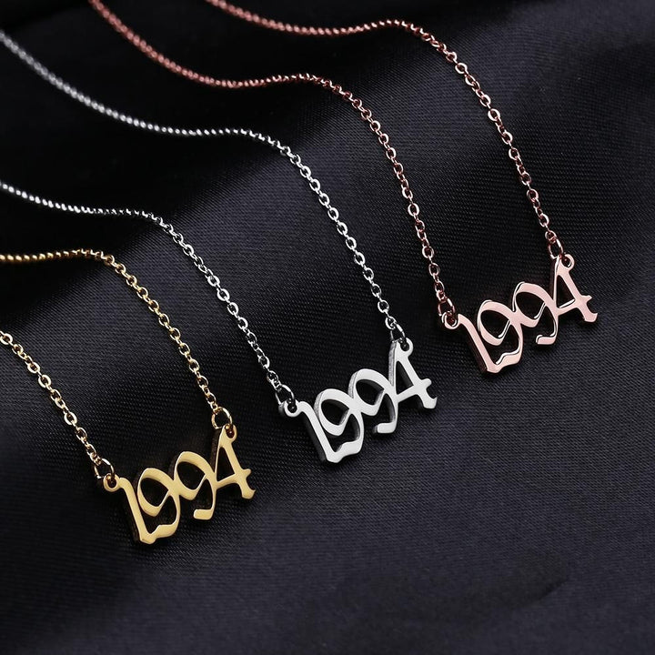 Three necklaces with the year "1994" engraved on them, in different colors: gold, silver, and pink.
