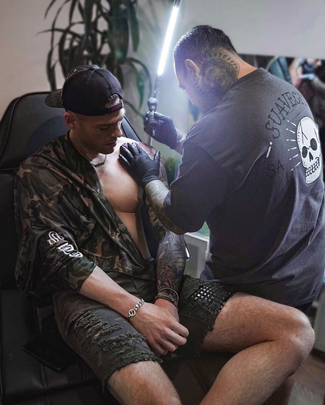 A tattoo artist is carefully applying a tattoo to a client&