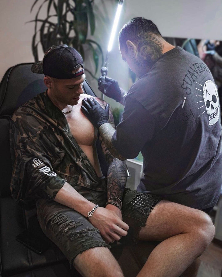 A tattoo artist is carefully applying a tattoo to a client&